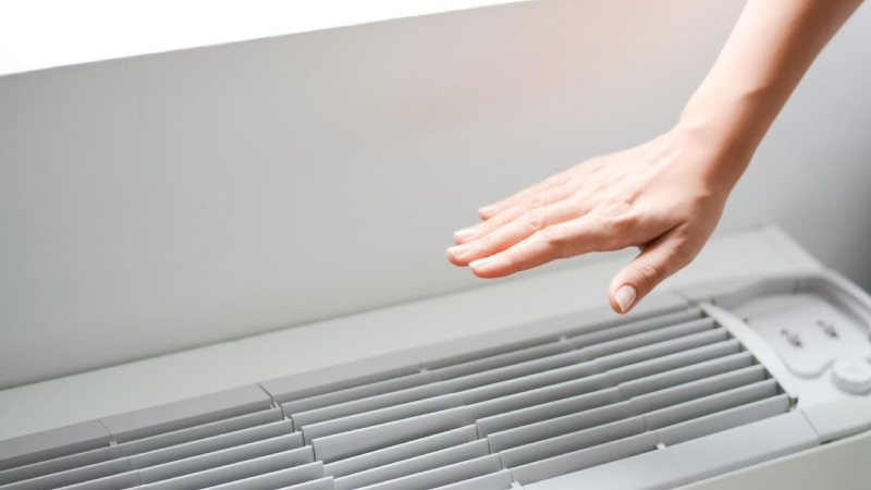 A person is touching the air vent of an indoor unit.