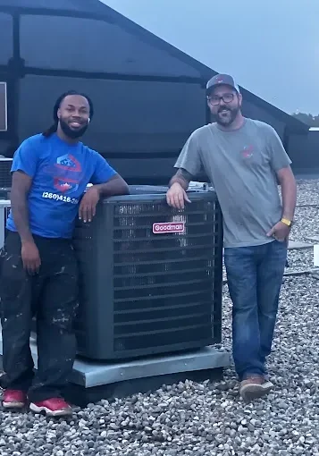 Two men standing next to a large air conditioner.